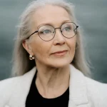 Staršia žena s okuliarmi a blond vlasmi.